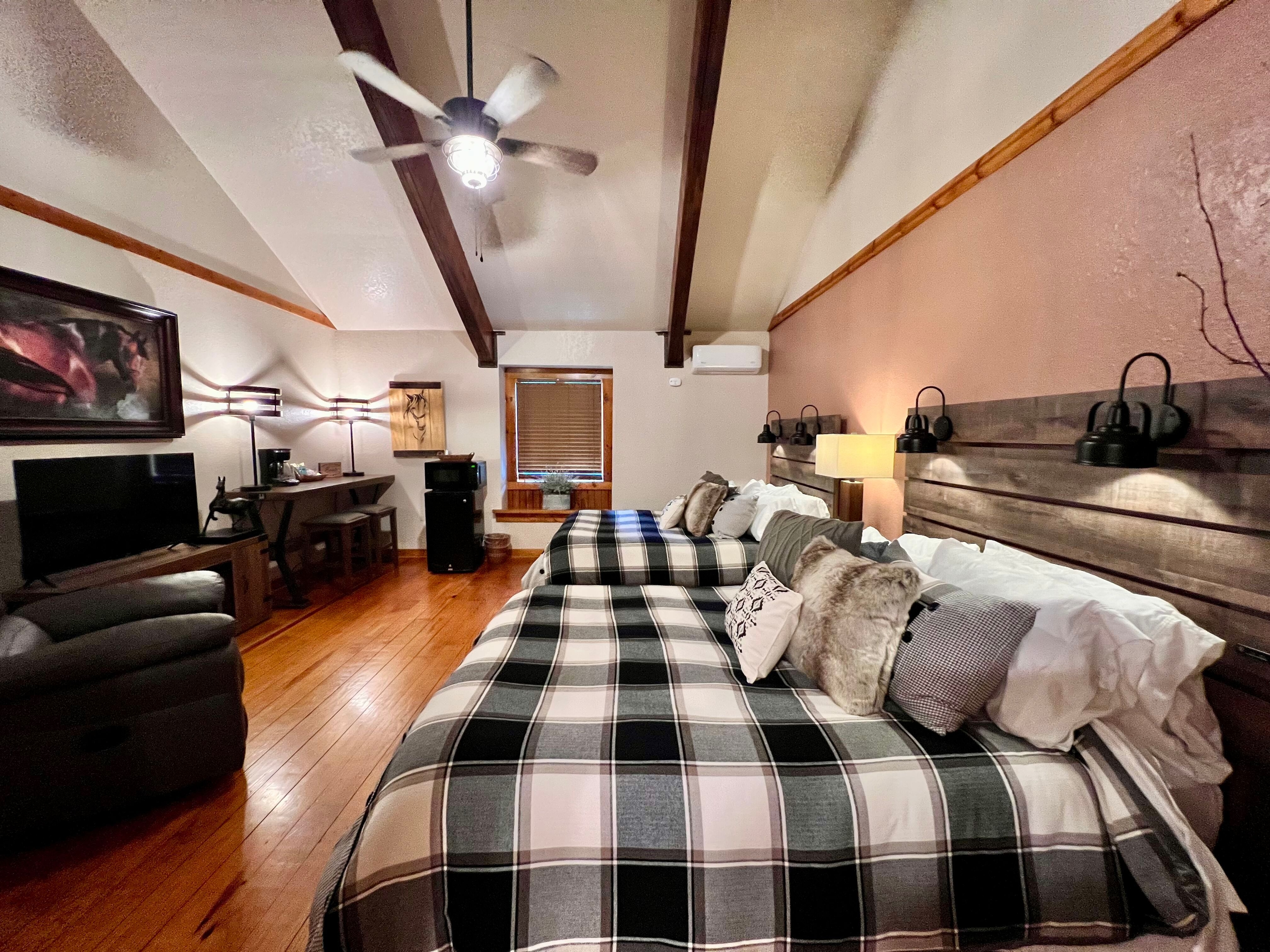 Spacious room with high ceilings, ceiling fan, two queen beds, leather recliner, and flat-screen TV