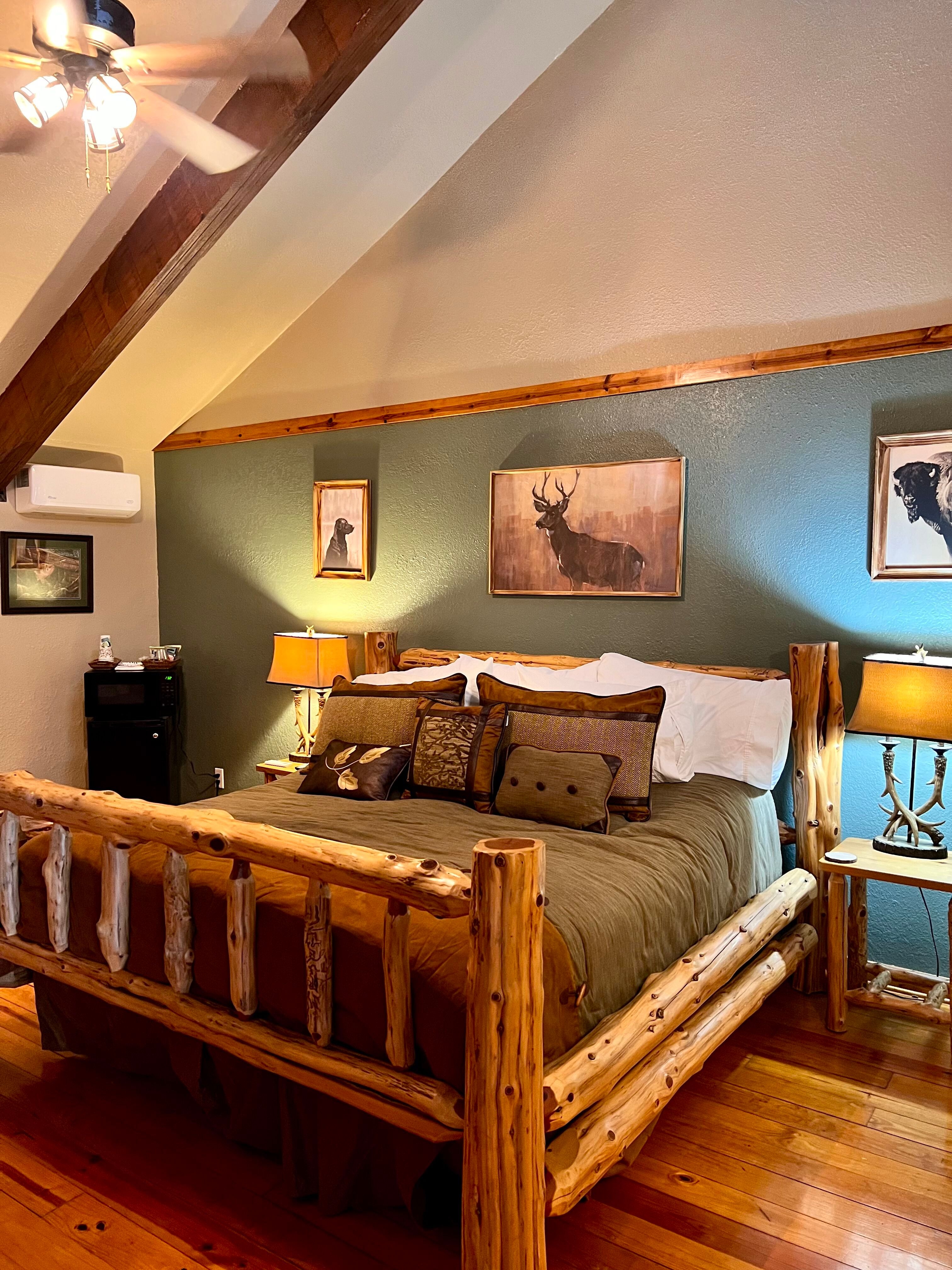 Gorgeous log bed with decorative pillows, matching nightstands with antler table lamps, and pictures of wildlife on wall