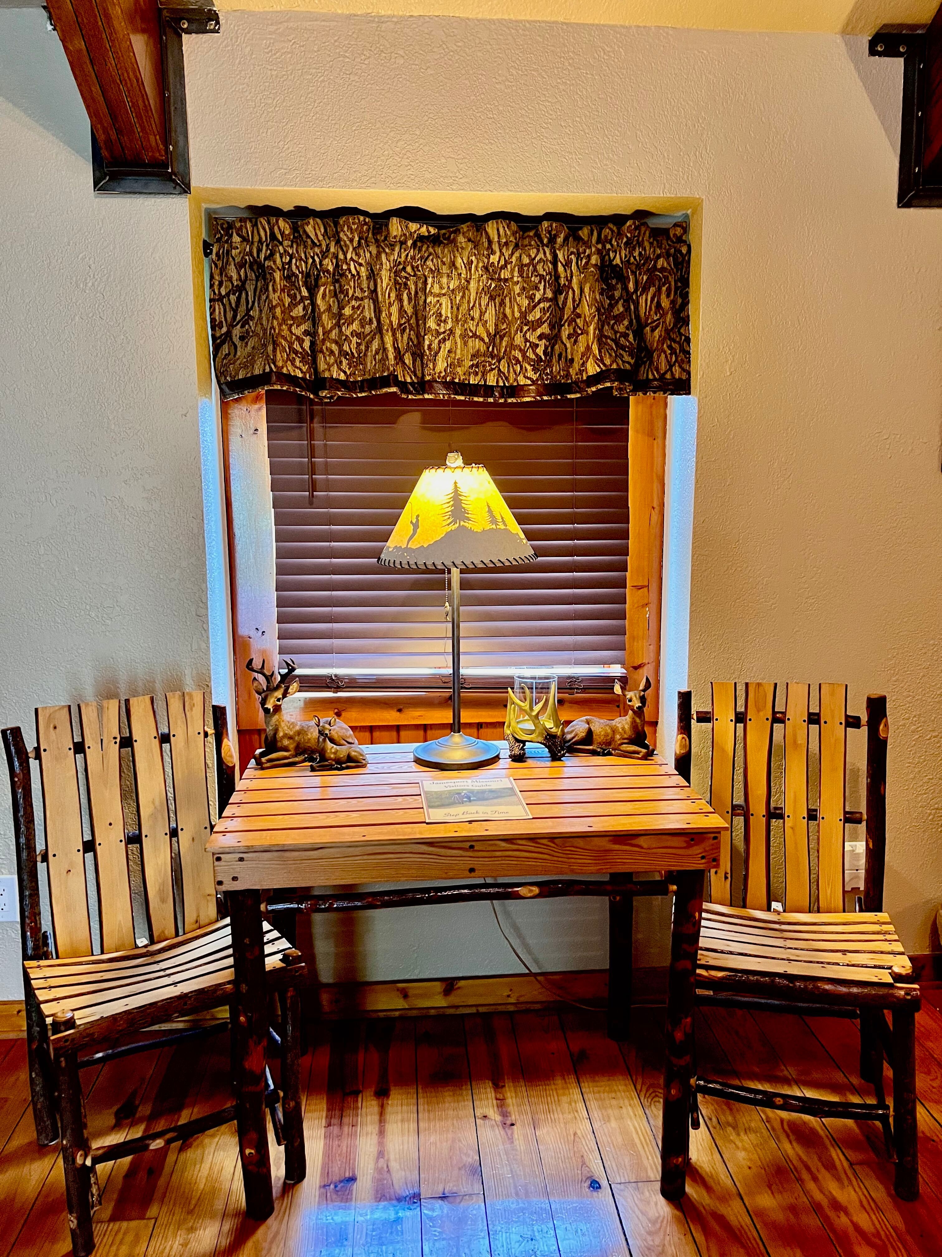 Handcrafted log table and chairs for two in front of a window, beautifully stained hardwood floor