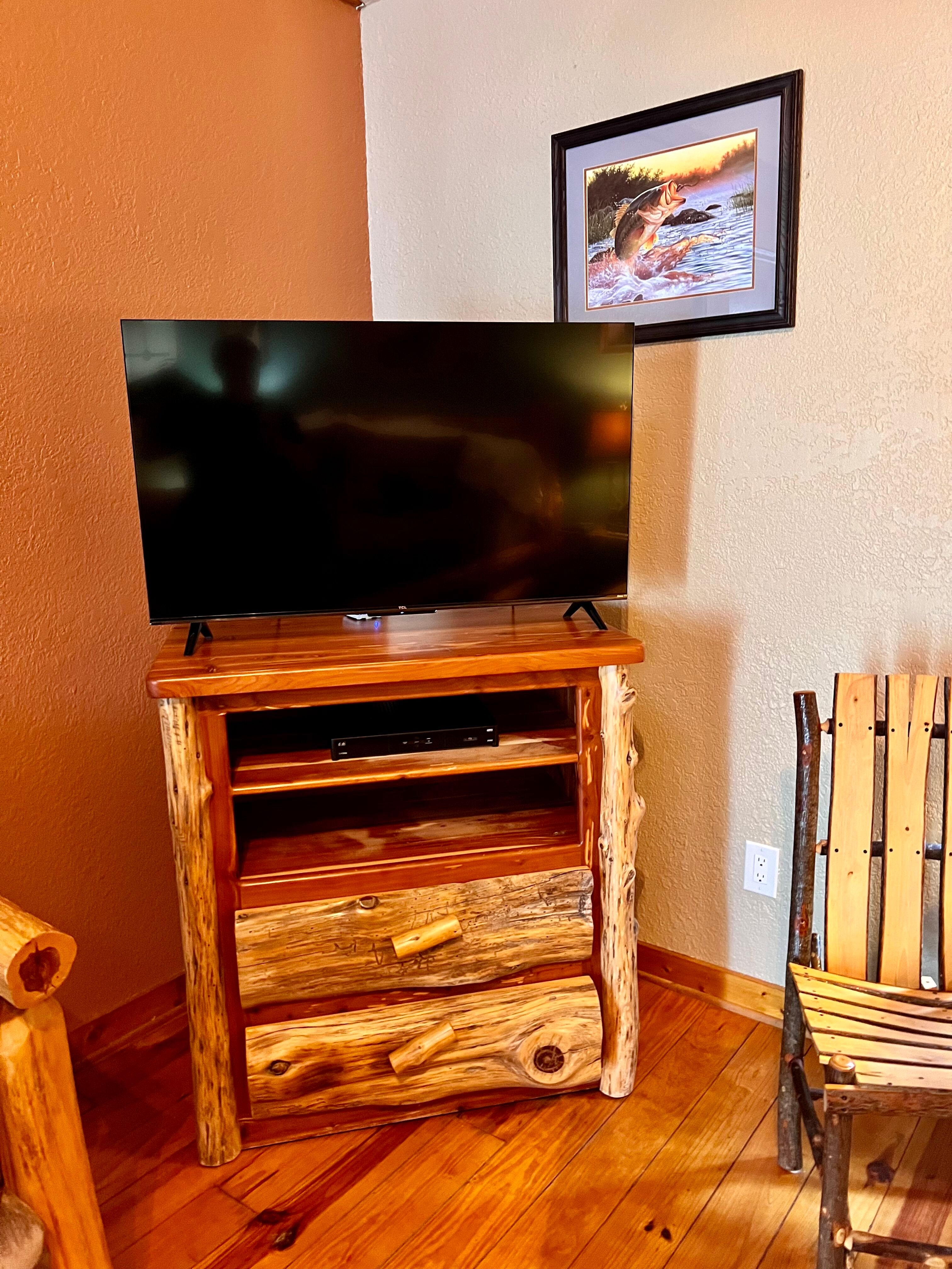 Handcrafted log TV stand with drawers and shelves topped with flat-screen TV