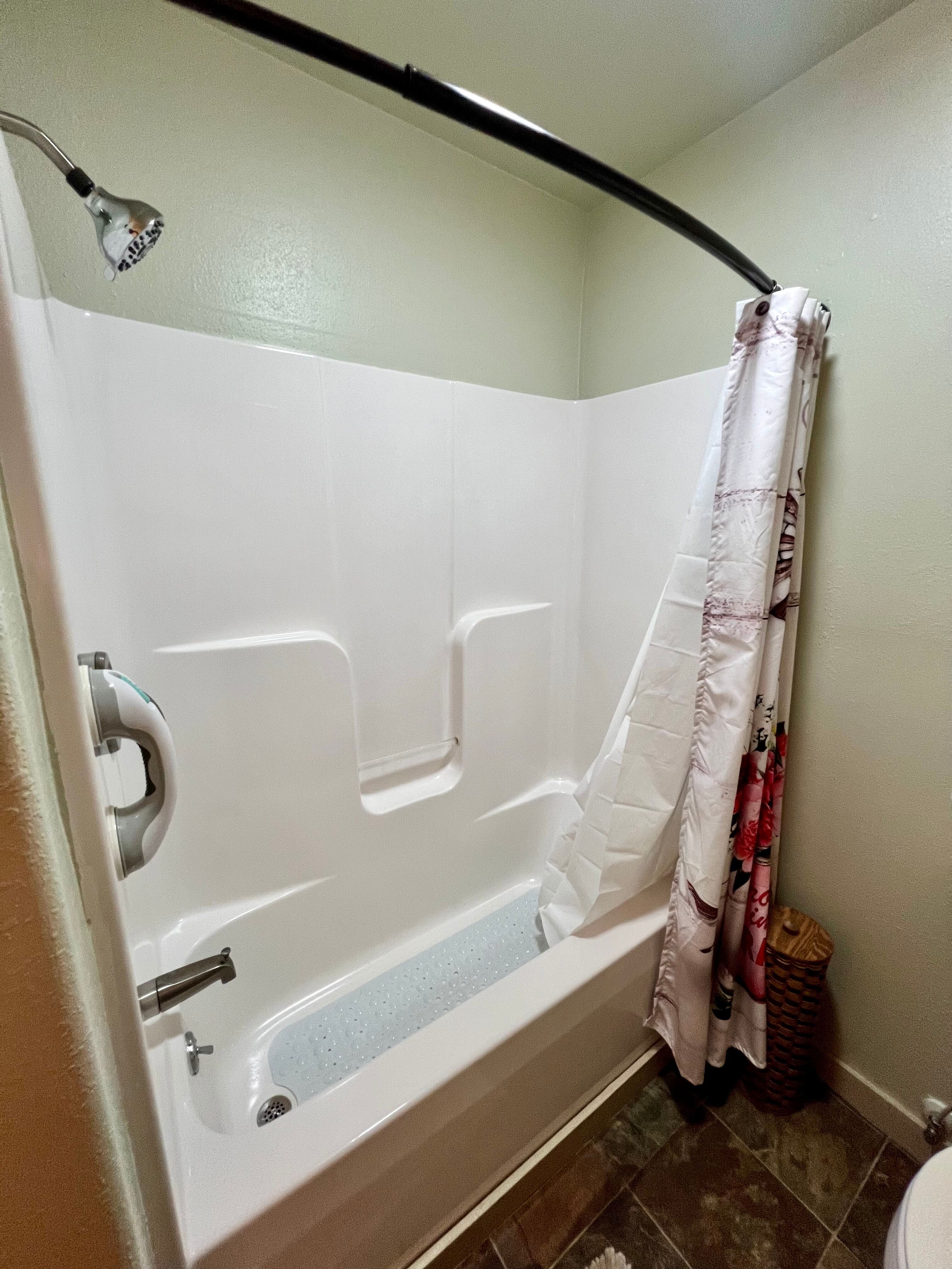 Immaculate white shower with silver fixtures and curved shower curtain rod